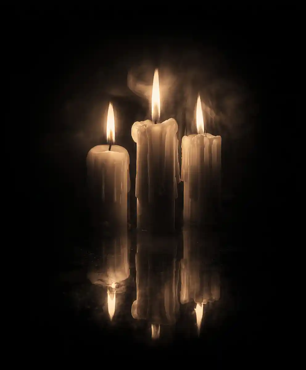Close up of three glowing candles in darkness