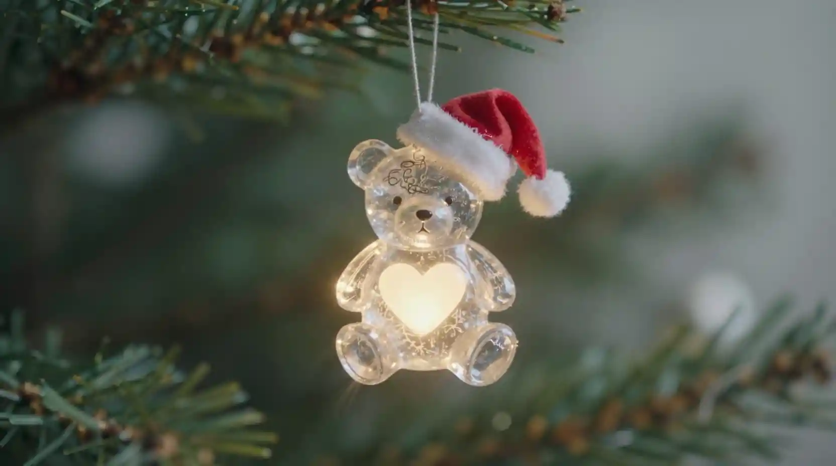 Teddy bear christmas ornament glowing on a festive tree branch
