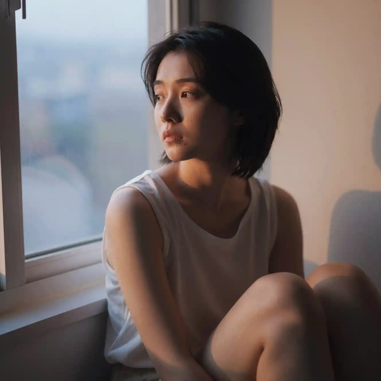 Young woman by a dawn window in soft quiet light
