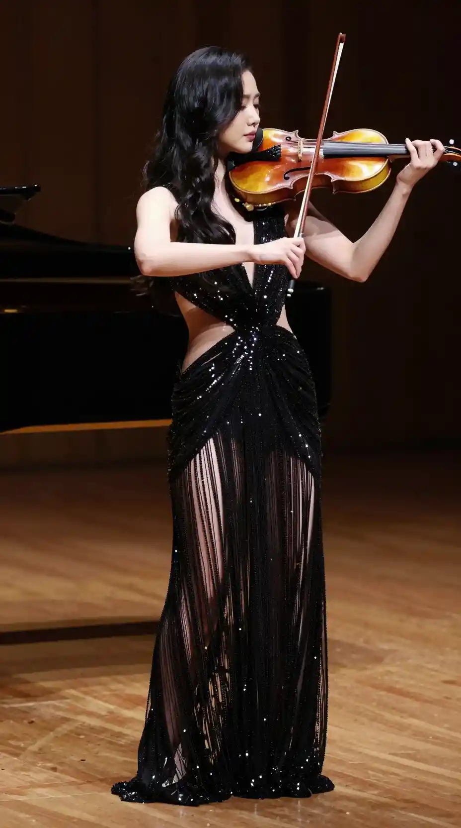 Elegant violinist performing on stage in shimmering black dress