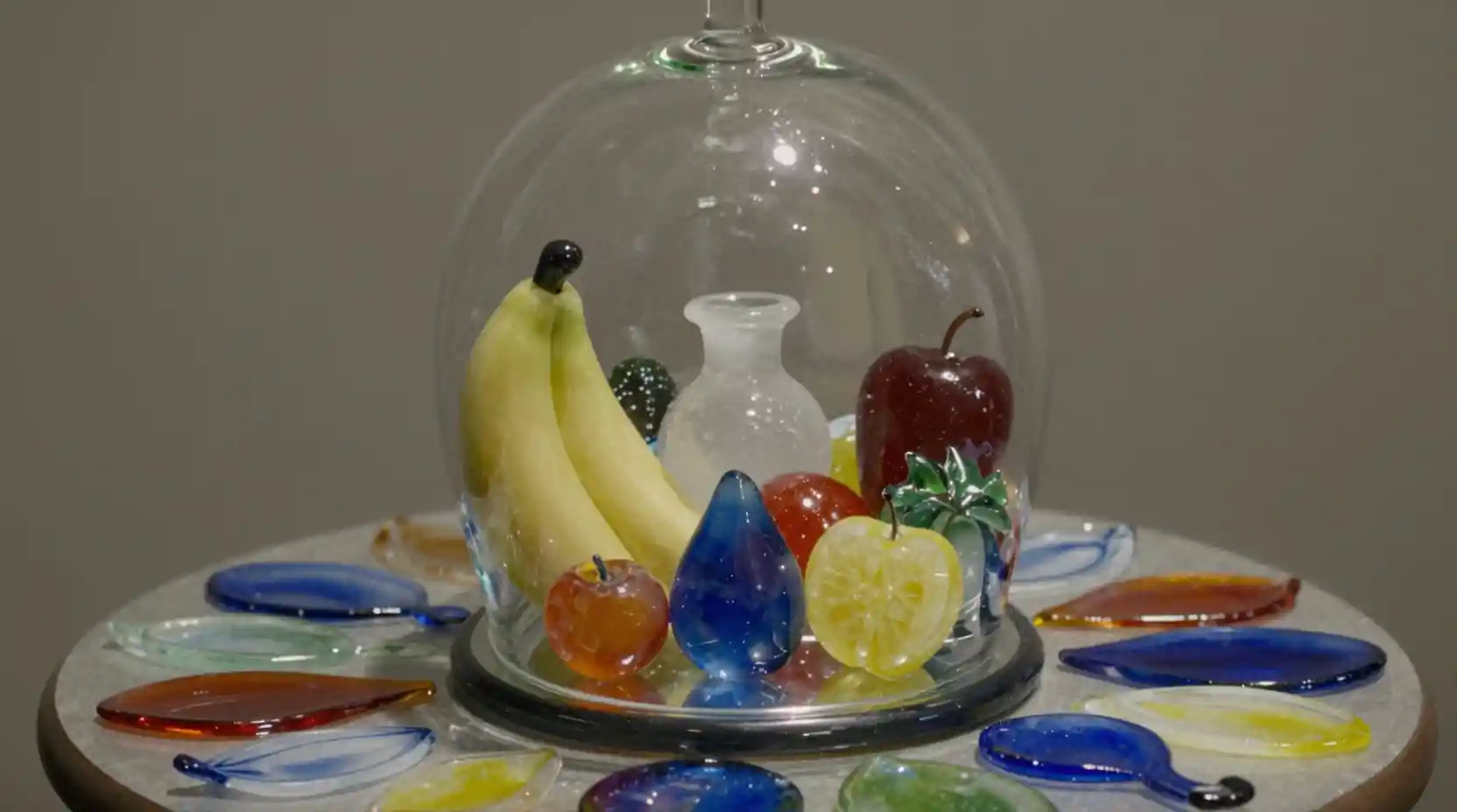 Fruits en verre surréalistes disposés sur une table en verre colorée