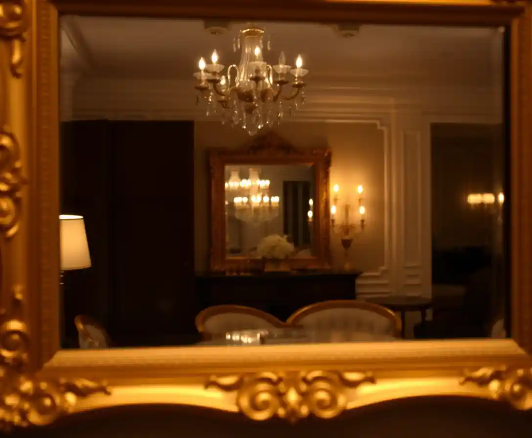 Espelho com moldura dourada refletindo um ambiente elegante com iluminação suave