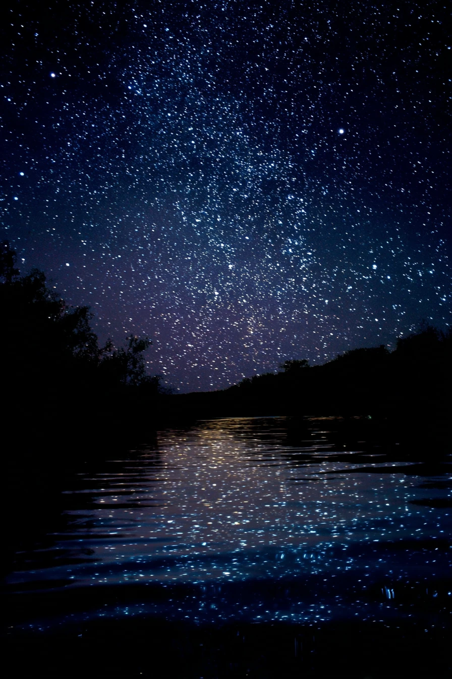Person gazing at stars reflected on a quiet night river