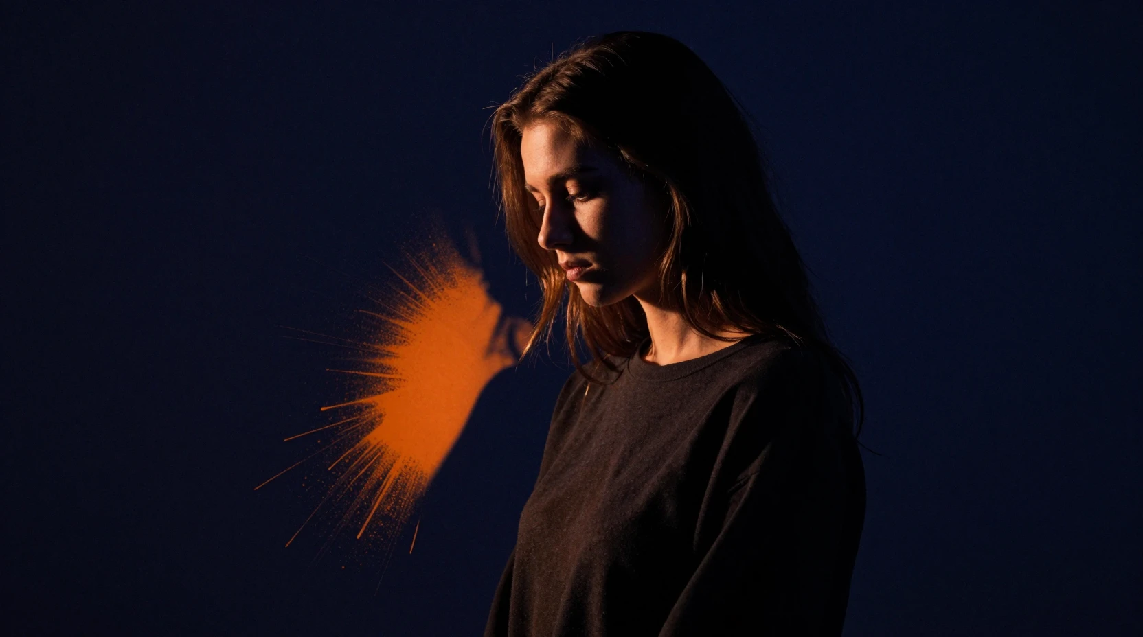 Young woman in dramatic chiaroscuro against dark indigo background