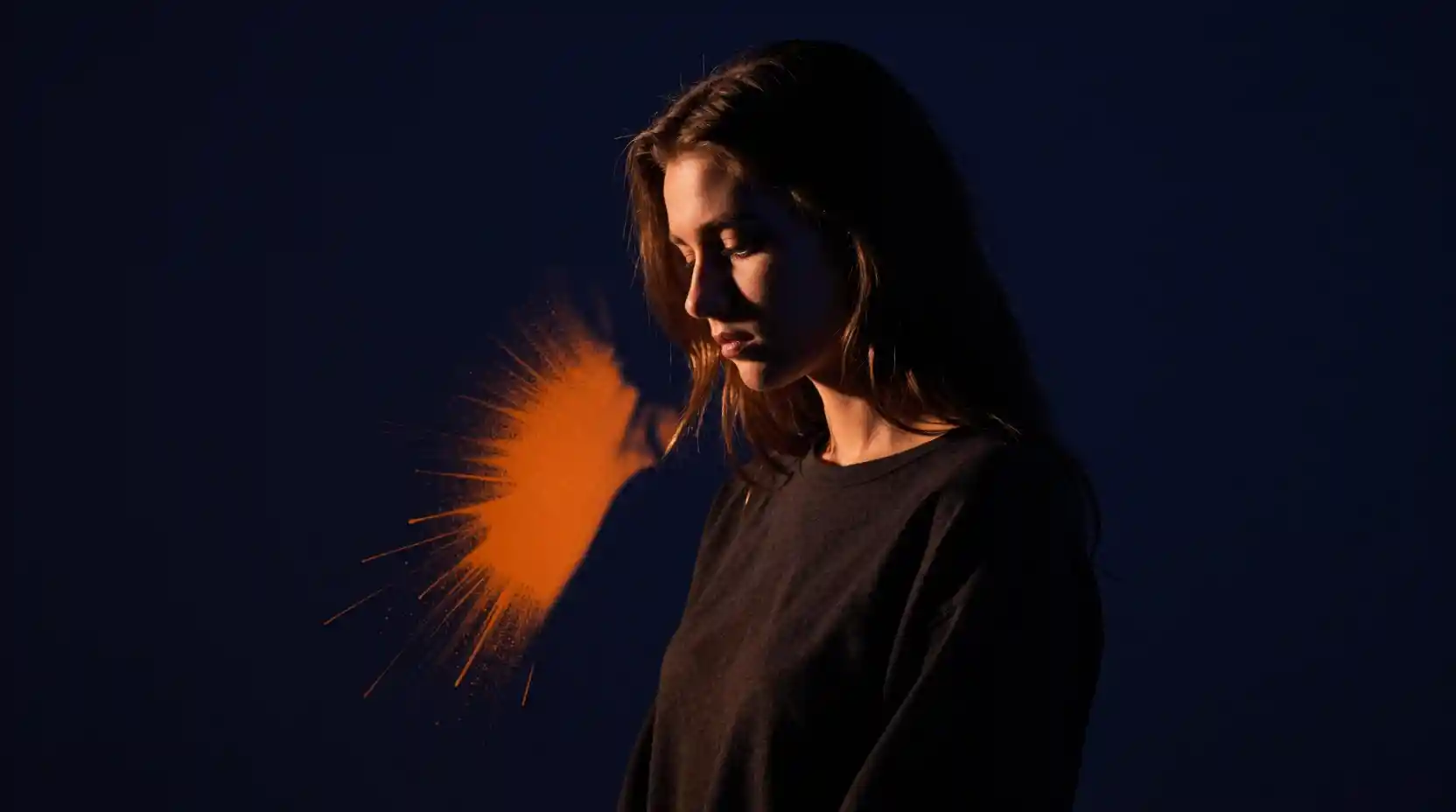 Young woman in dramatic chiaroscuro against dark indigo background