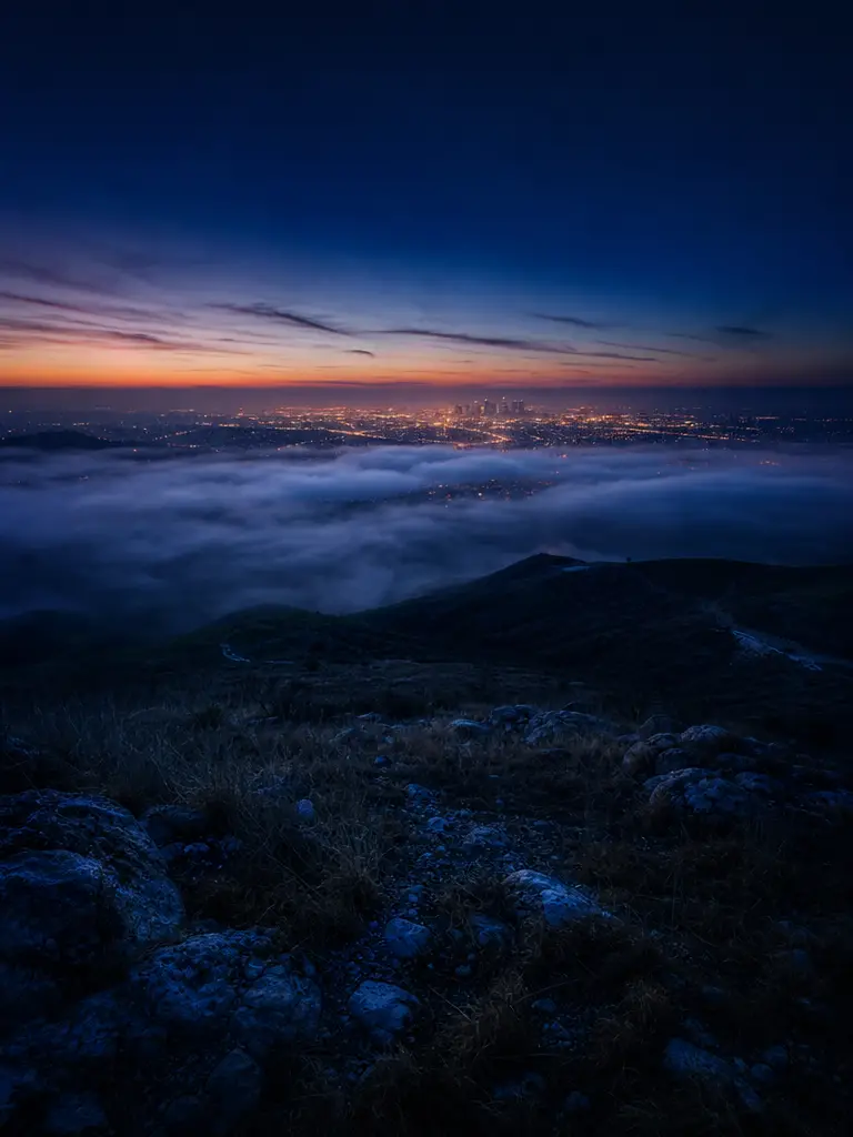 Colina enevoada com vista para o horizonte distante de uma cidade iluminada