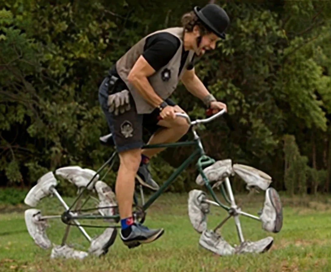 Man riding a quirky shoe wheeled bicycle in green park