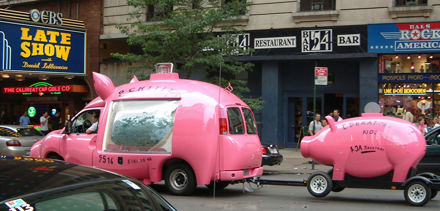 Fourgon rose en forme de cochon avec remorque assortie dans une rue animée