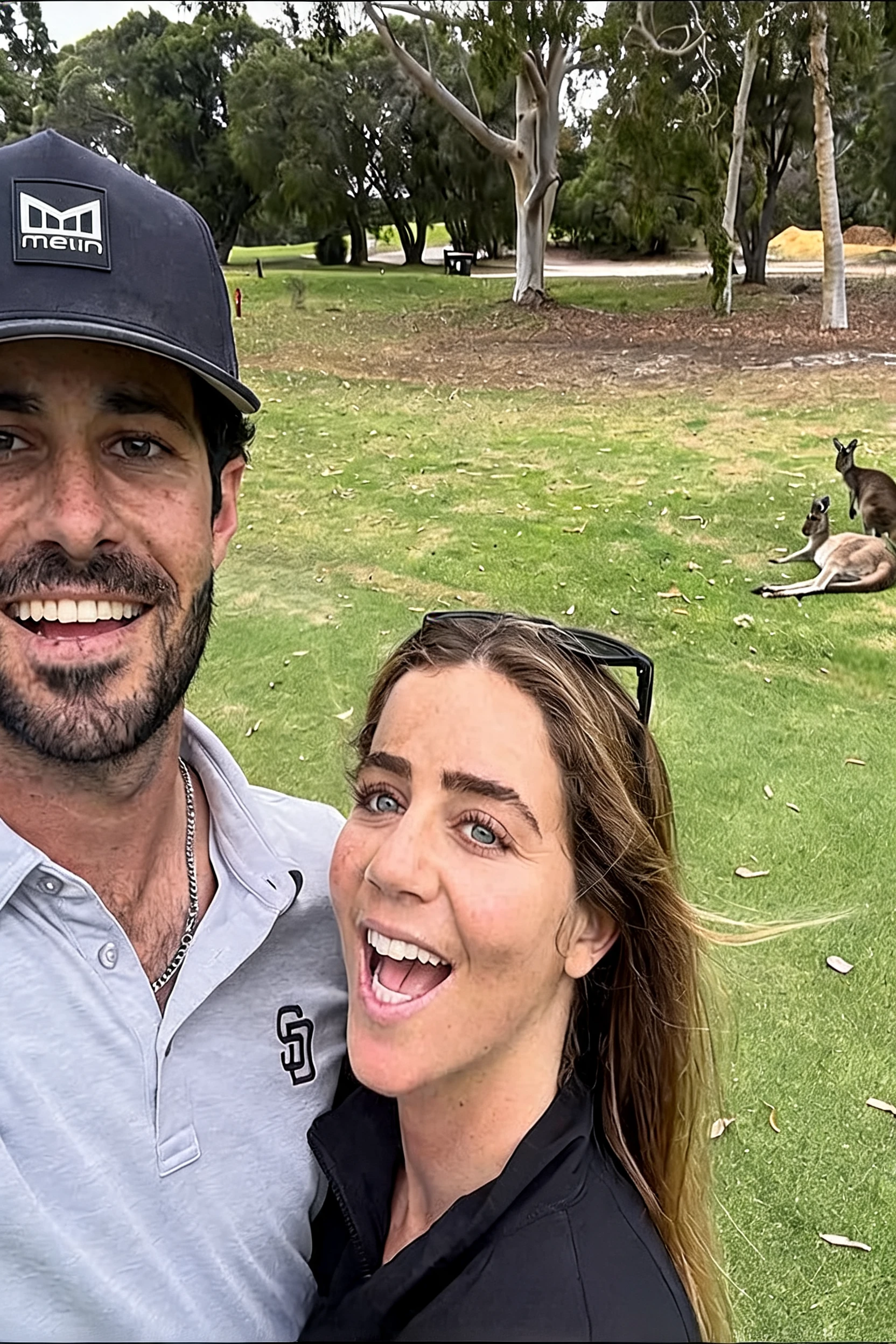 Casal alegre faz selfie com cangurus em um parque verde