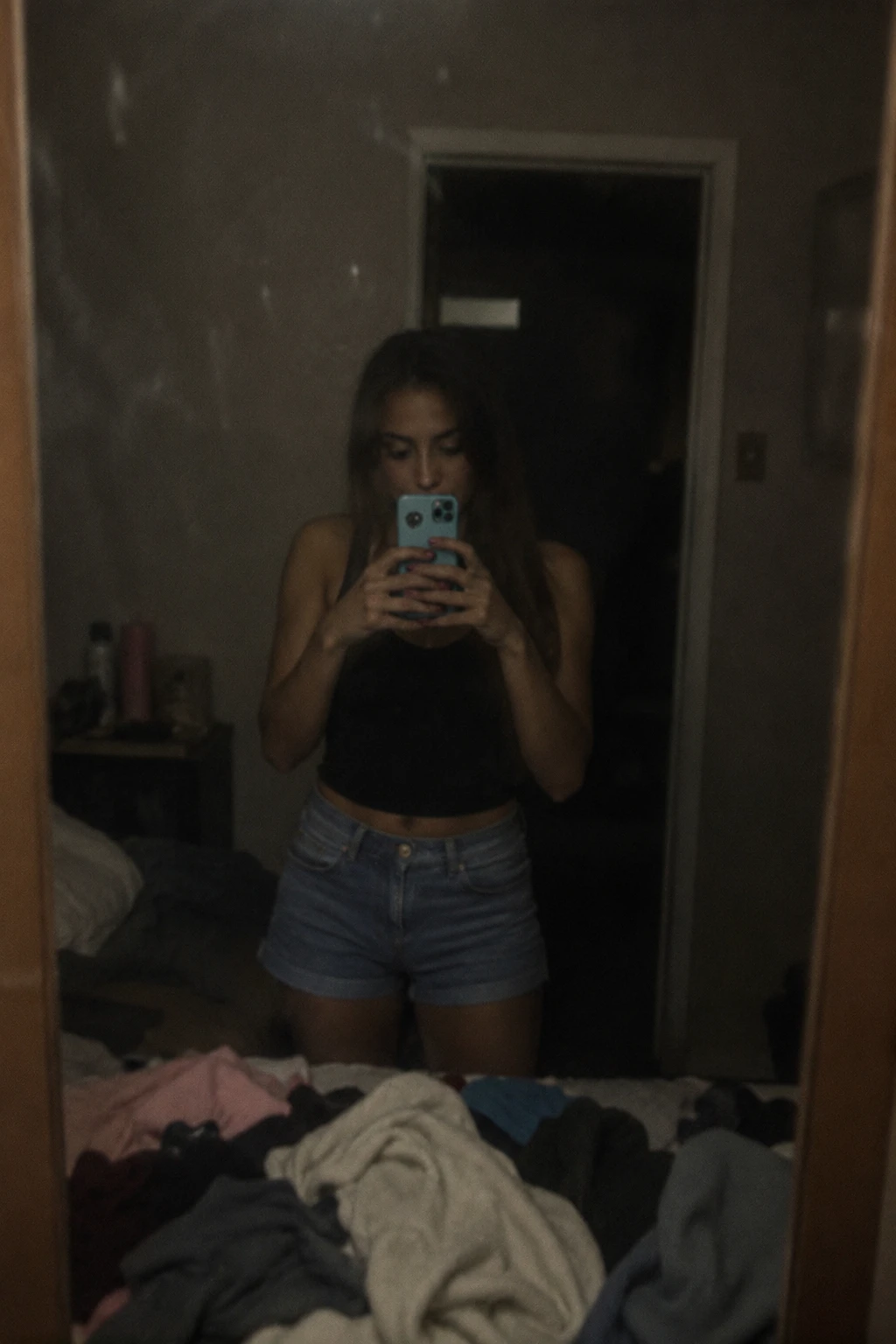 Femme prenant un selfie dans le miroir dans une chambre en désordre