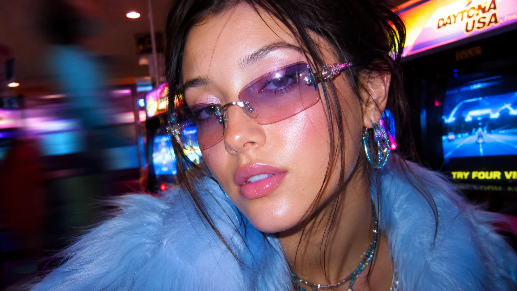 Portrait d’une fille avec lunettes teintées dans une salle d’arcade de nuit
