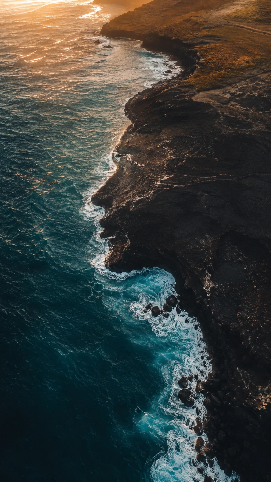 Aerial view of waves shaping a rugged coastal face