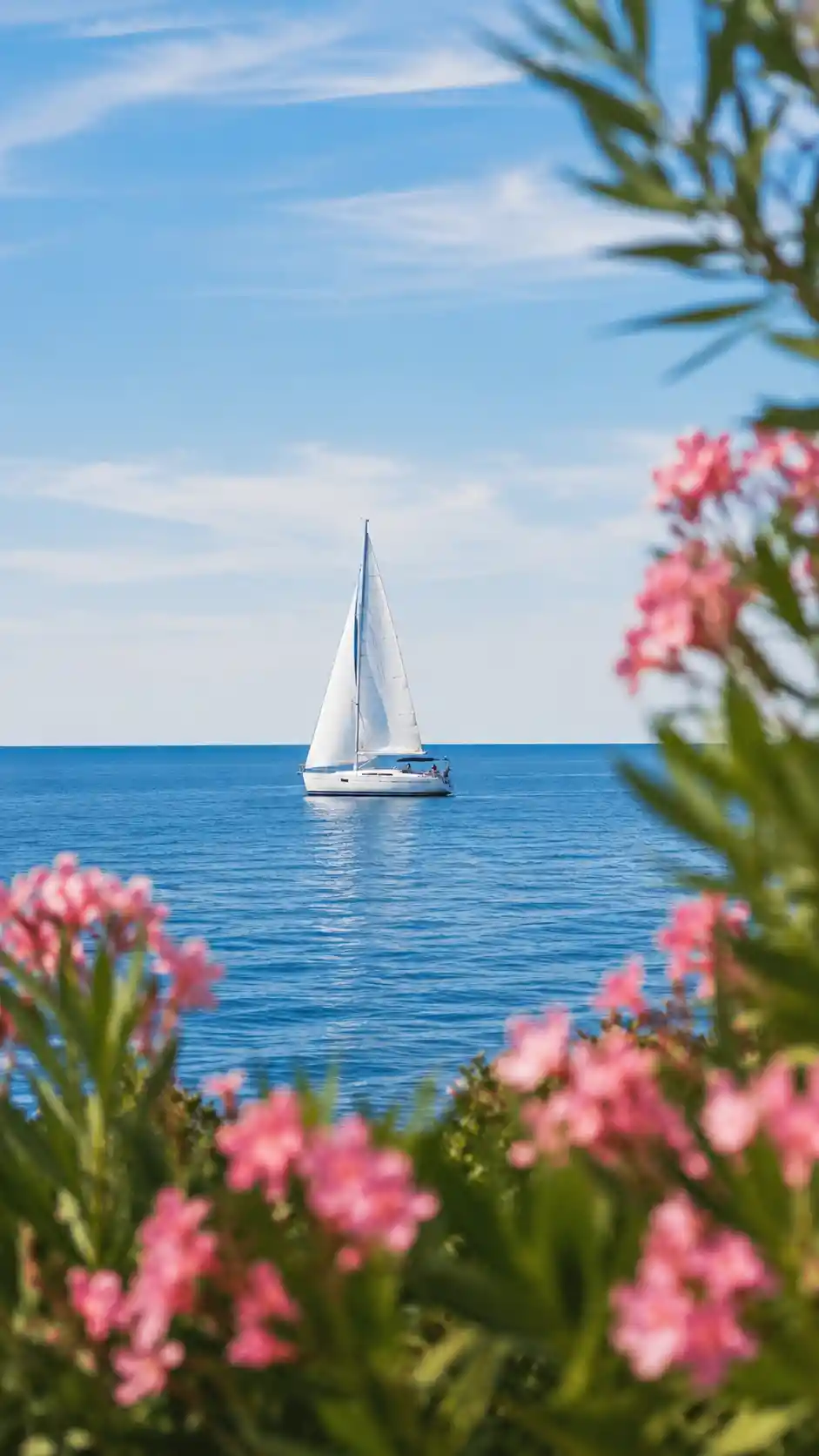 柔らかな花々に縁取られた、穏やかな青い海に浮かぶ白い帆船