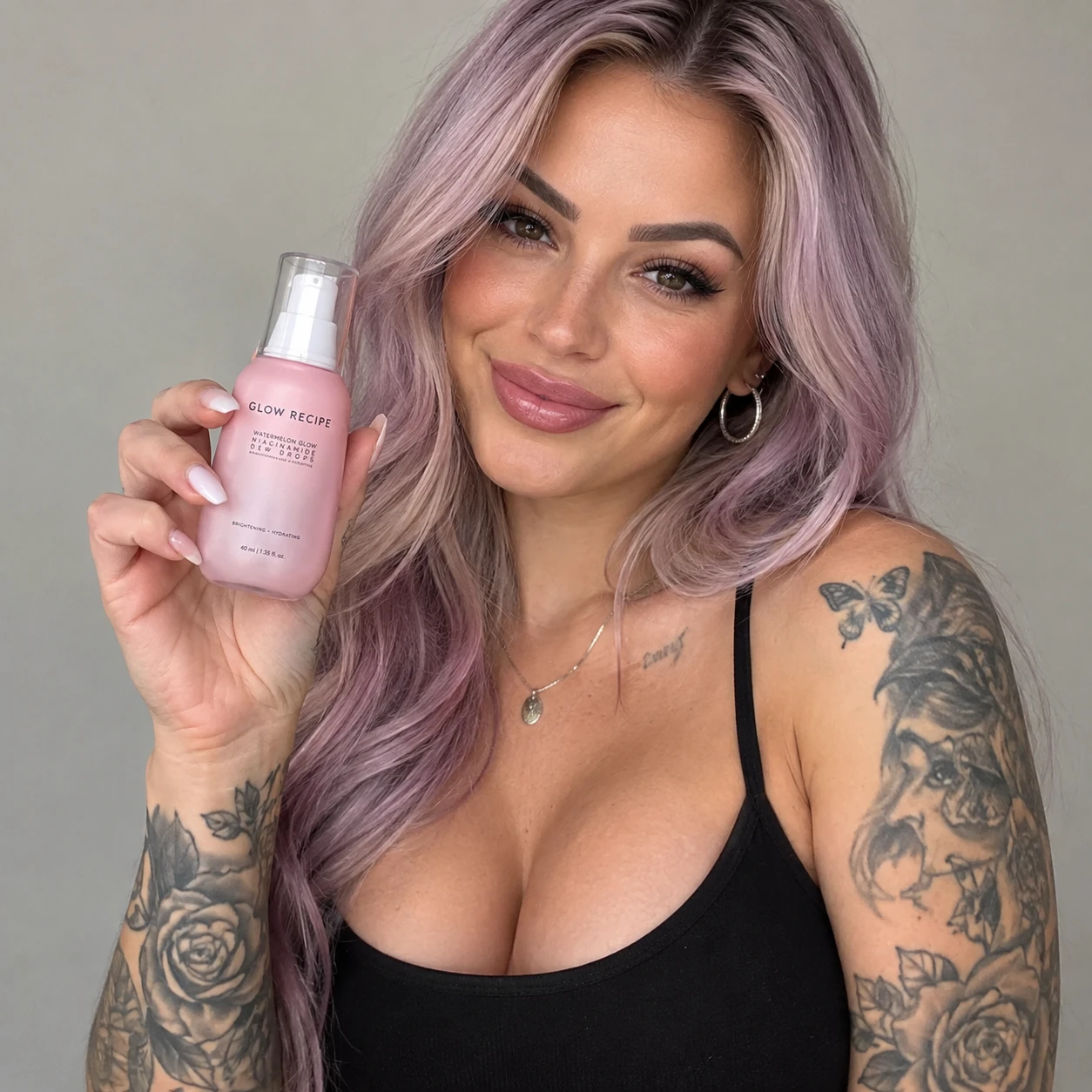 Selbstbewusste tätowierte Frau präsentiert ein Beauty-Produkt-Porträt