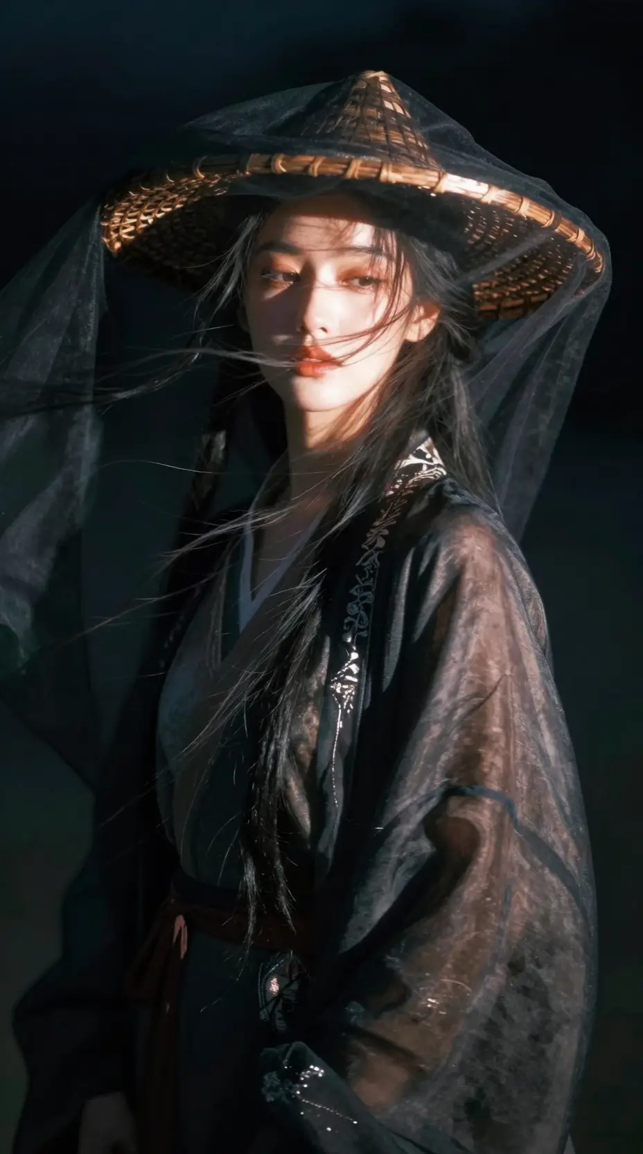 戴著編織帽、髮絲隨風飛揚、身穿絲綢長袍的蒙面女子