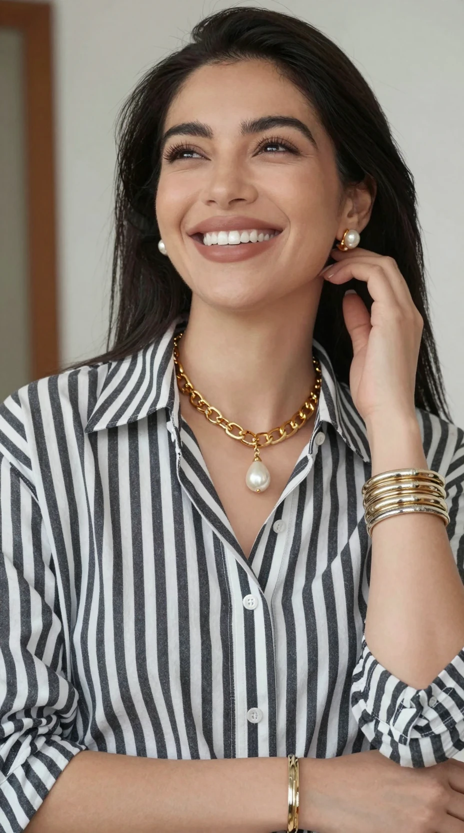 Mulher sorridente olha para cima com camisa listrada e joias douradas