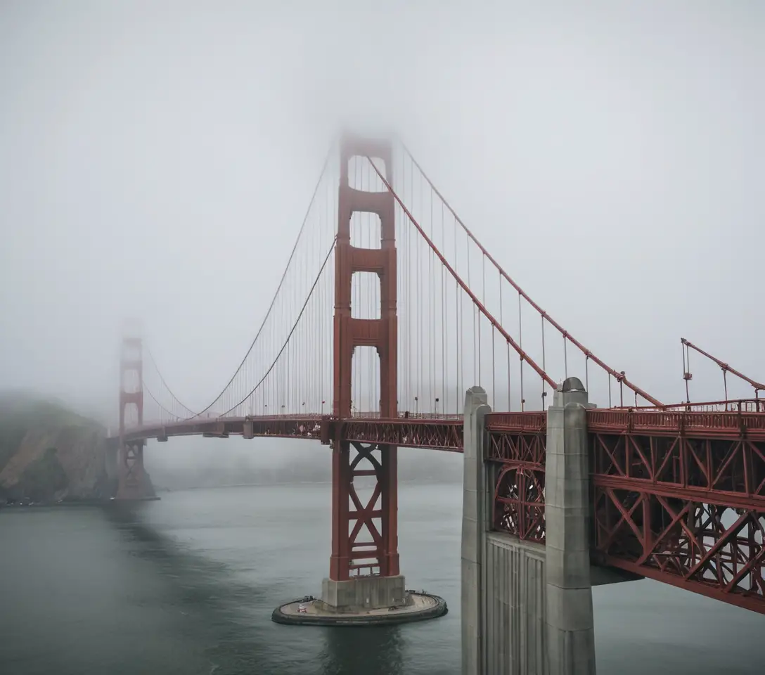 The Golden Gate Bridge Emerges Through Fog Over Reflective Water