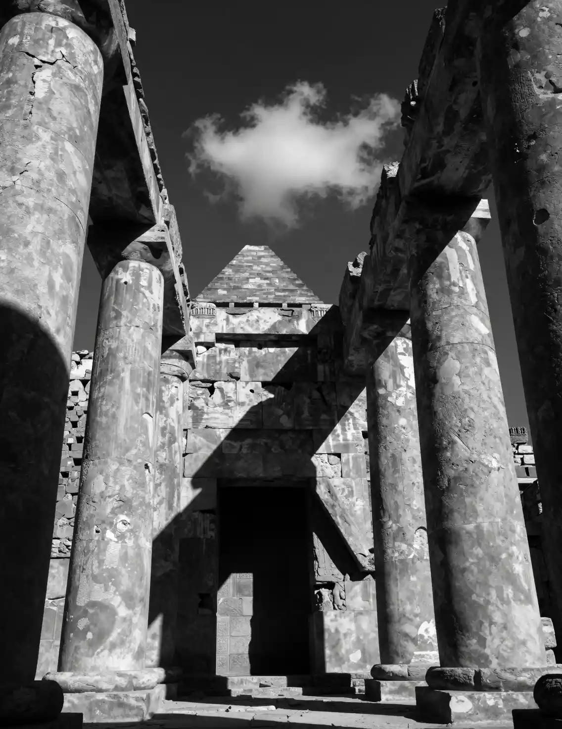 Ancient stone columns rise beneath a brooding sky in monochrome
