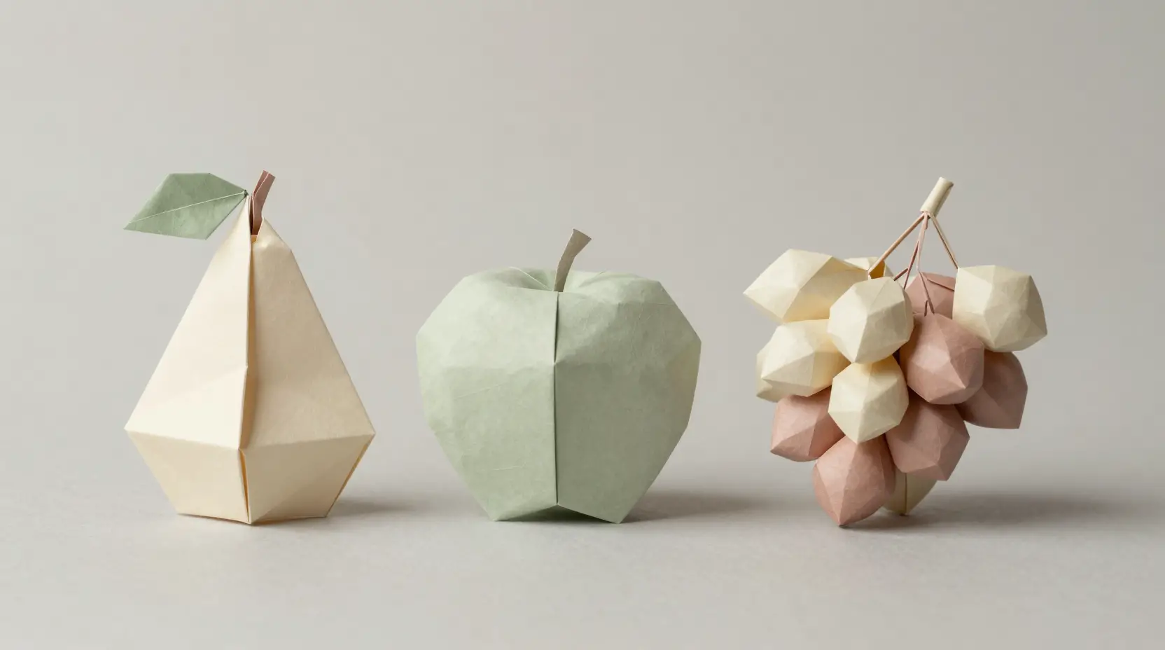 Pera, maçã e uvas em origami numa natureza-morta minimalista de papel