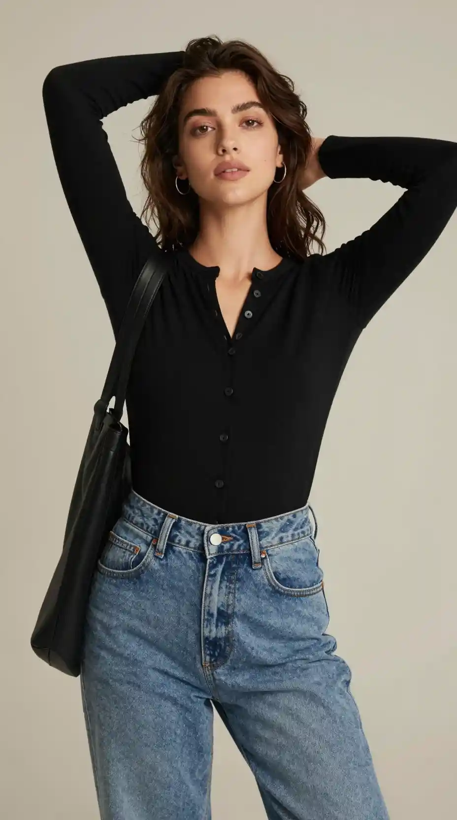 A relaxed portrait in a buttoned black top against a neutral backdrop