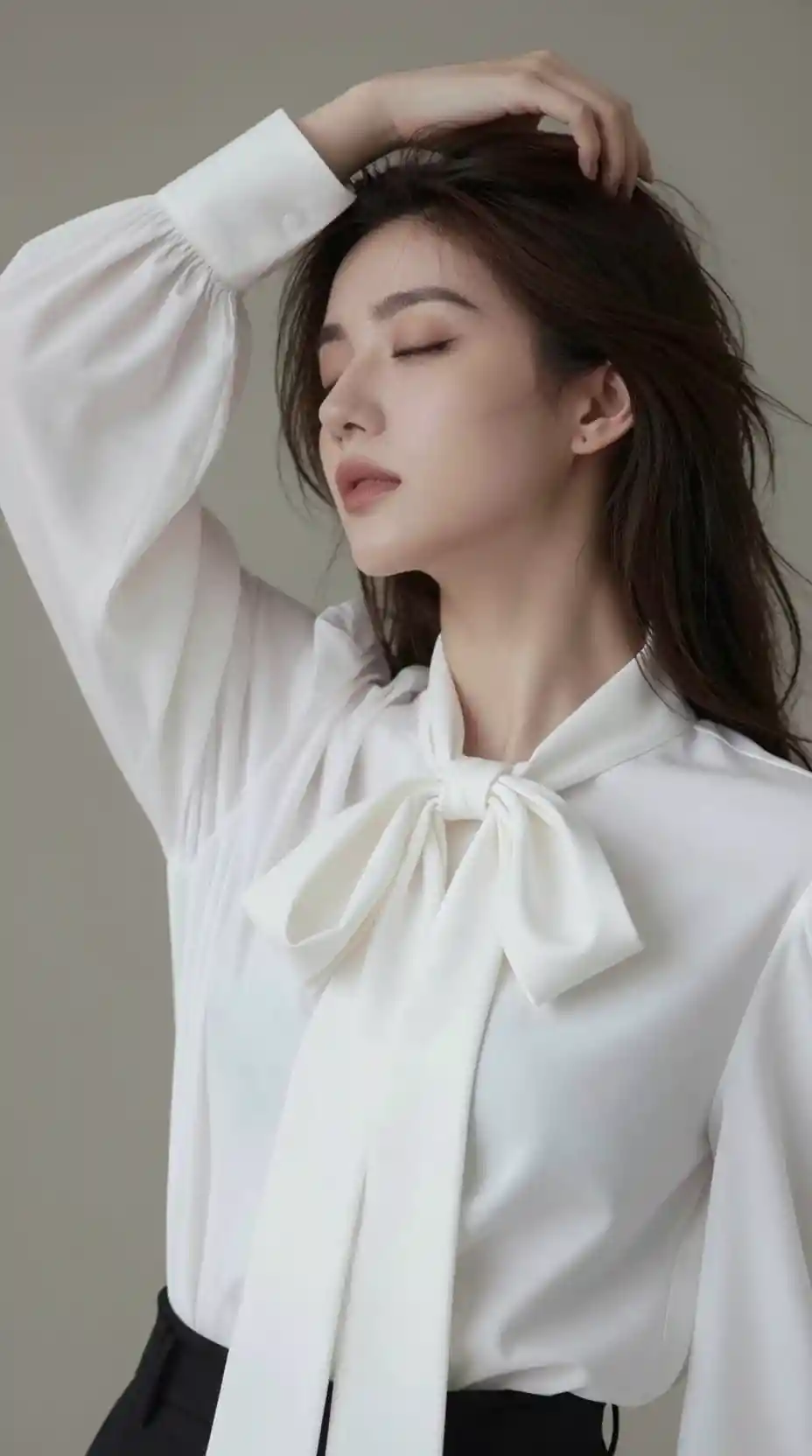 Una joven con una blusa blanca se toca suavemente el cabello con los ojos cerrados