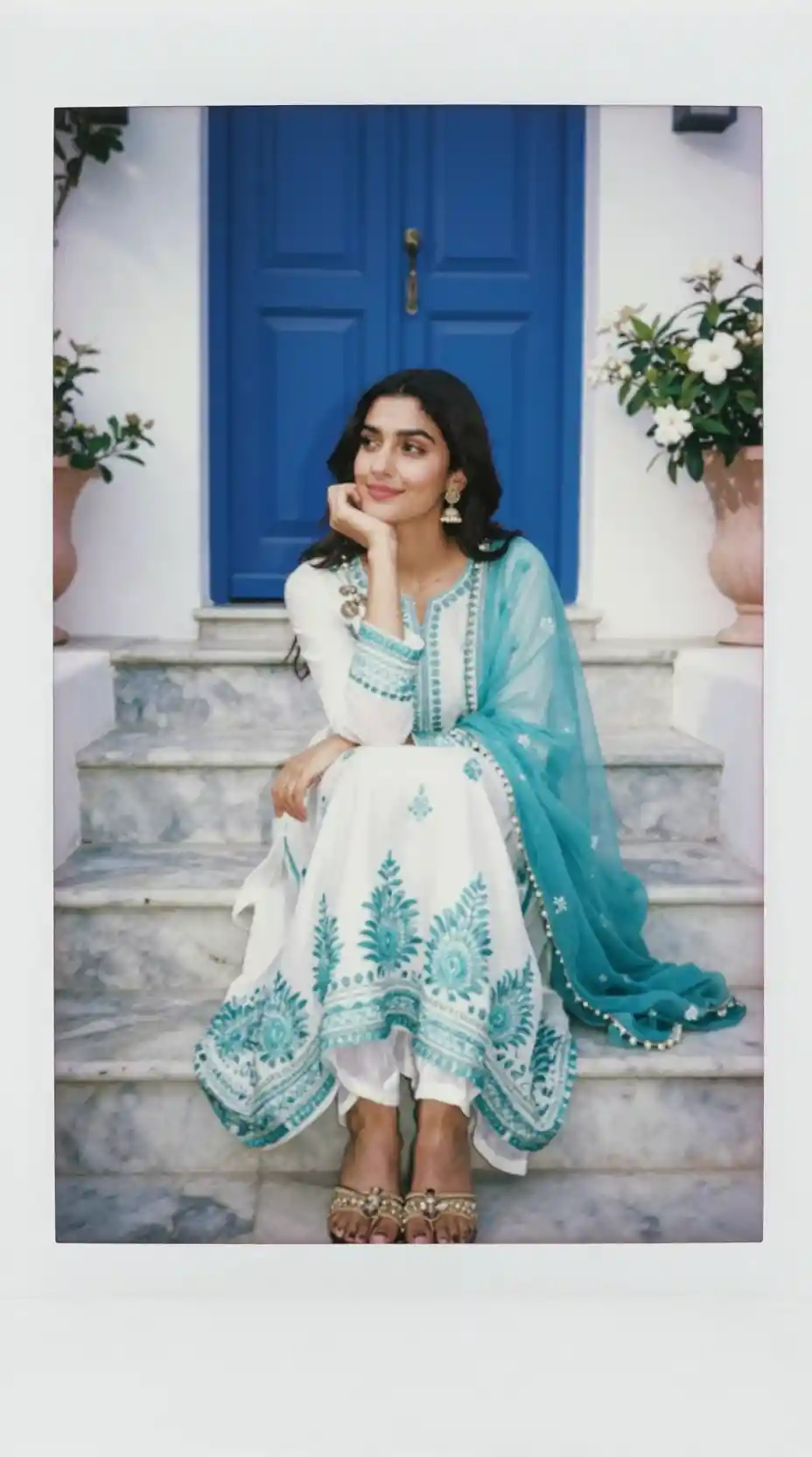 Young woman in an embroidered Anarkali suit sits on marble stairs